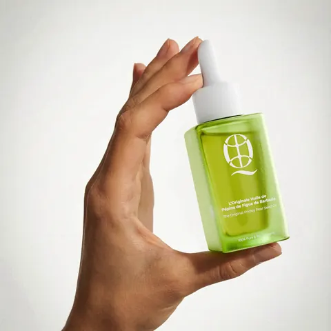 Huile d'argan Quedebio tenue en main sur fond uni