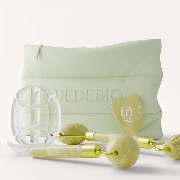La pochette Quedebio à emblème gaufré, à côté du rouleau de jade, du gua sha et du support acrylique