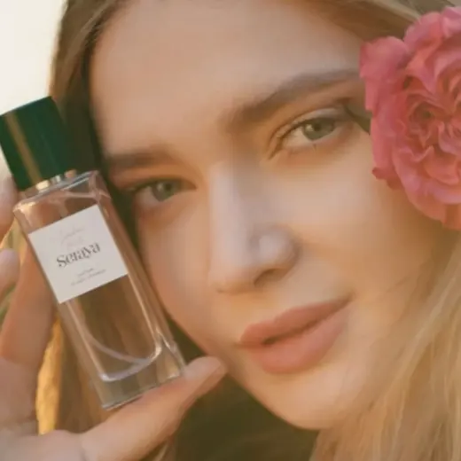 Portrait de campagne Seraya, mannequin tenant le flacon près de son visage, une rose dans les cheveux